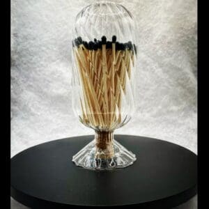 A glass vase with matches in it on top of a table.