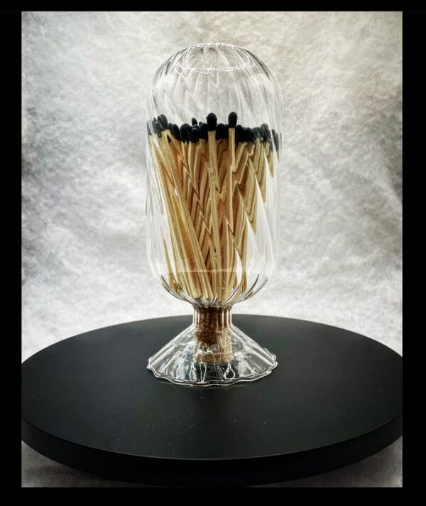 A glass vase with matches in it on top of a table.