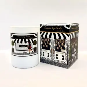 A Saturday Vibes candle in a white container next to its black and white patterned packaging, both labeled "candles by nicole.