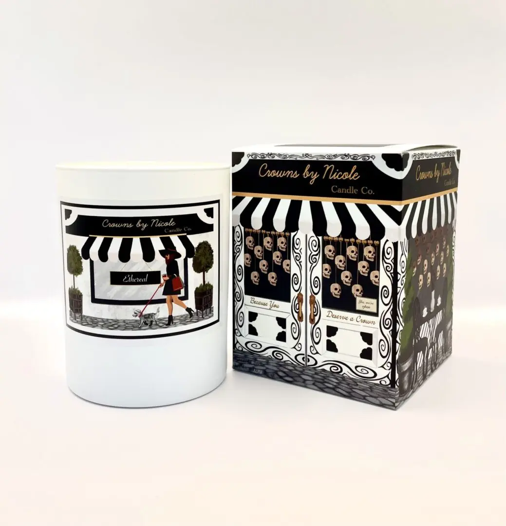 A Sass in Scarlett candle in a white container next to its patterned packaging box, both labeled "candles by Nicole.