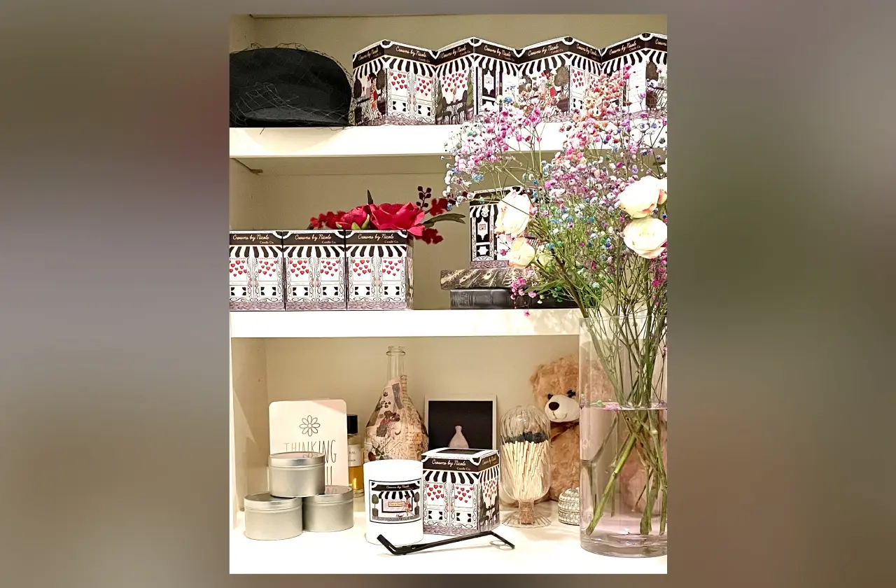 A cozy shelving unit with decorative boxes, flower arrangements in a vase, and various trinkets including a teddy bear and a lantern.